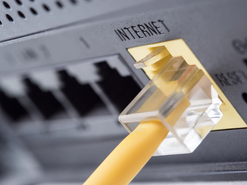 Gros plan sur un câble réseau Ethernet jaune connecté à un routeur ou modem internet
