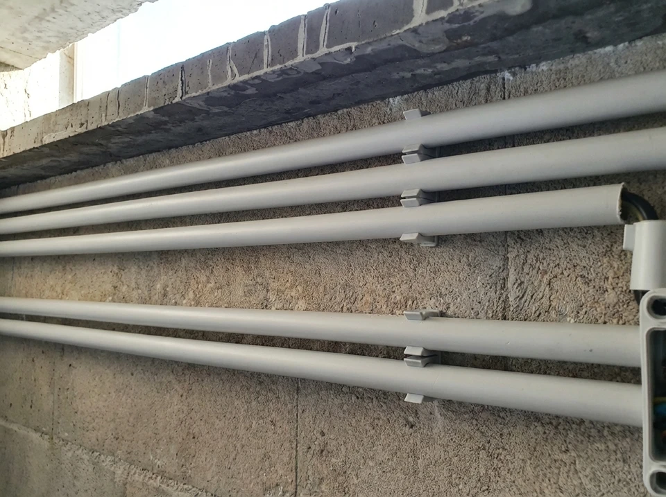 Garage vide avec mur en lambris de pin, tableau électrique mural avec disjoncteurs modulaires, compteur électrique jaune, conduits PVC apparent