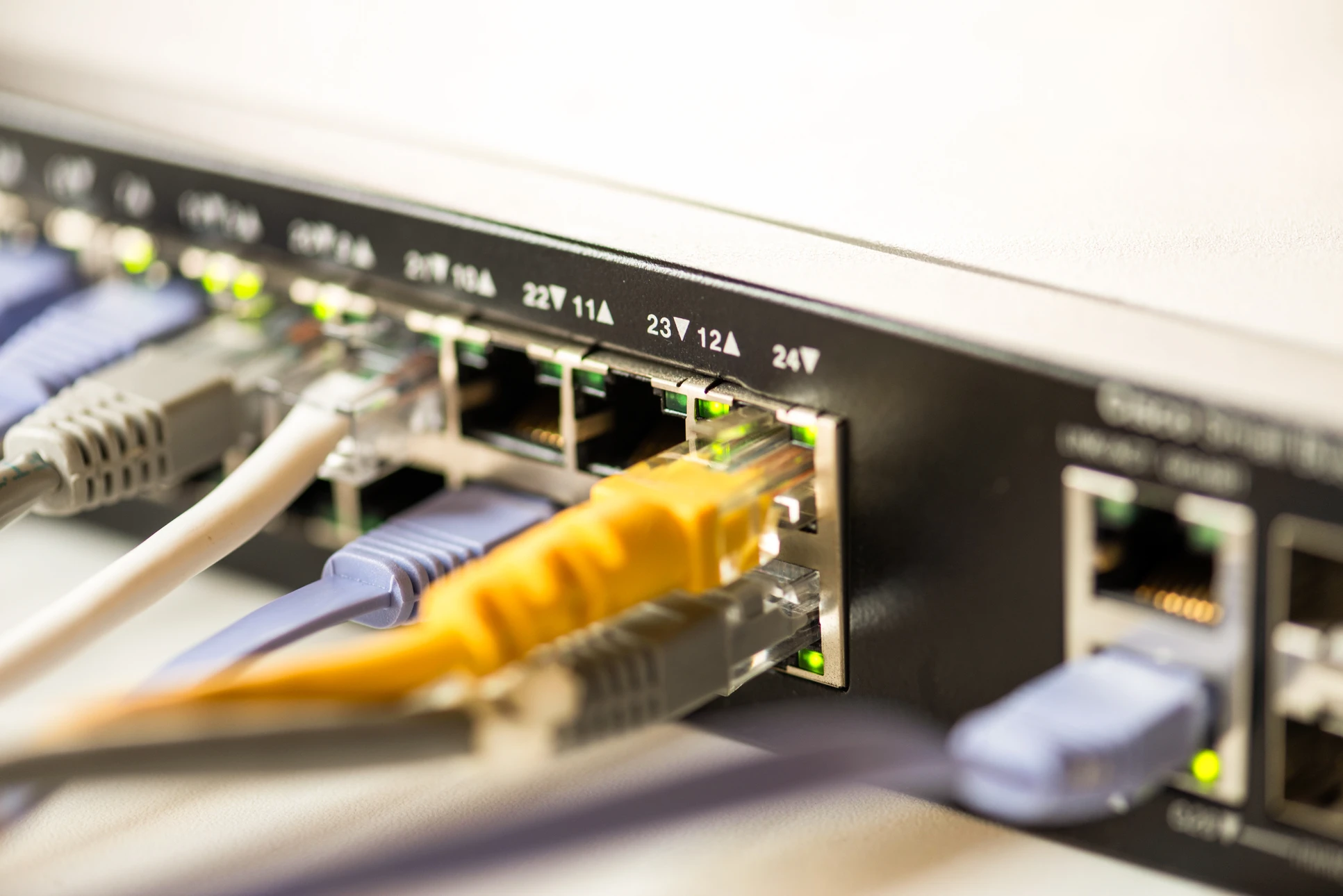 Gros plan sur un câble Ethernet RJ45 jaune transparent se connectant à un port réseau d'un équipement informatique gris