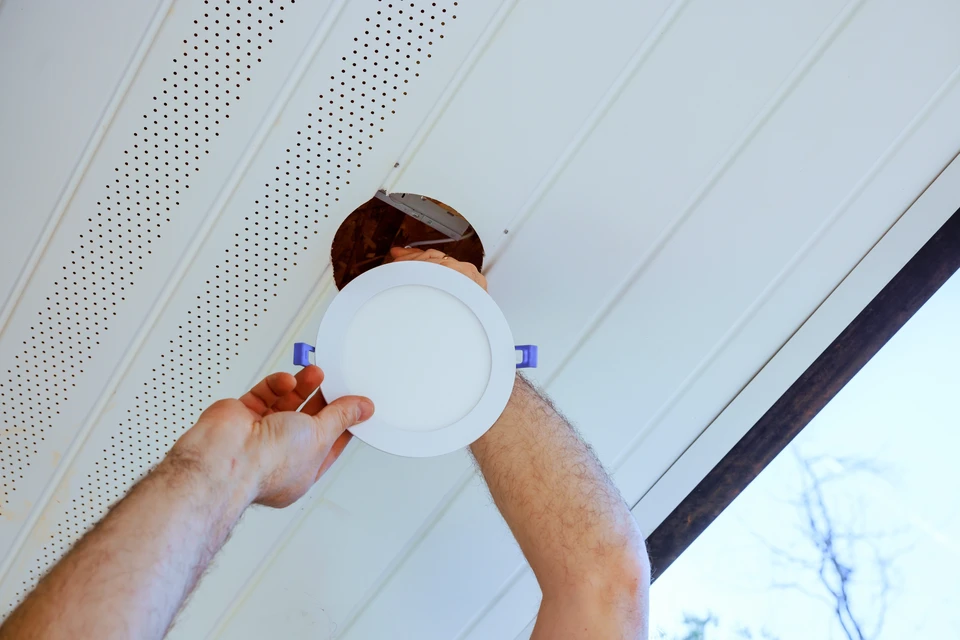 Artisan électricien installant un luminaire suspendu dans cuisine moderne en rénovation